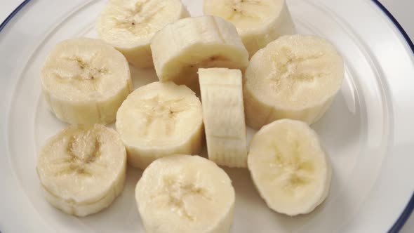 Sliced banana close-up. Fresh ripe slices on a white plate with a blue border.