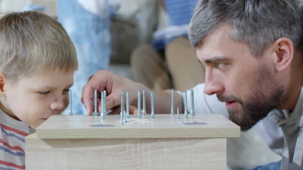 Father Showing Different Screws to Son