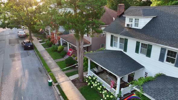 Aerial shot of small suburb town street. Pride flags and American flags hanging in front of quaint h