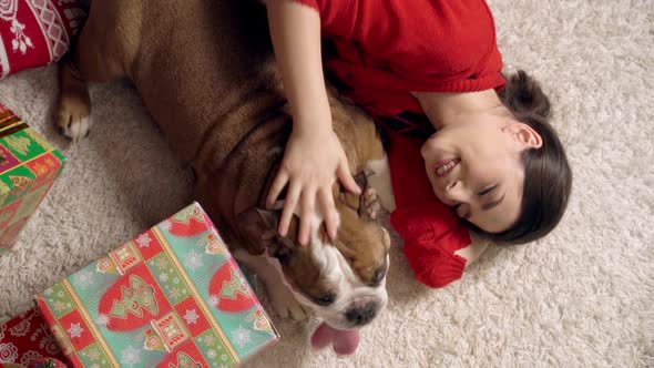 Charming Girl Plays Cute Funny Bulldog Under Christmas Tree