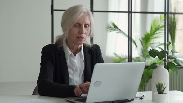 Tired Elderly Businesswoman Suffering From Eye Strain After Working on a Laptop in the Office