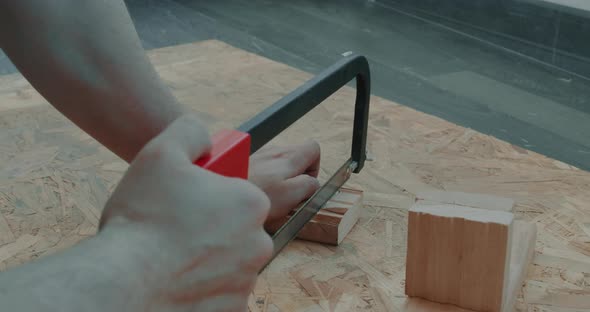 A Man Sawing Wood Board with Hand Saw