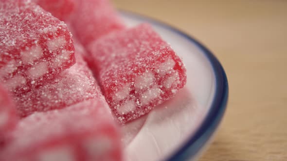 Red sweets candy in a plate on a wooden table