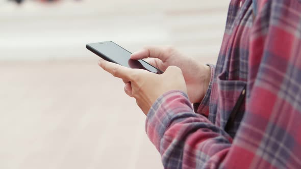 Asian man walking and using smartphone checking social media on the street in Thailand.