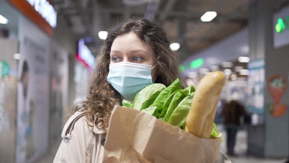 Woman Walks in Shopping Mall Holding Paper Bag with Products