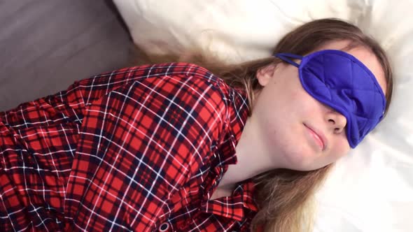 Young woman wearing sleep mask is turning to the side
