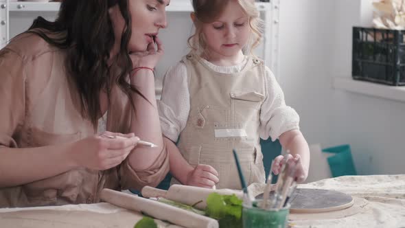 Portrait of Mother and Little Girl Shaping Clay Together