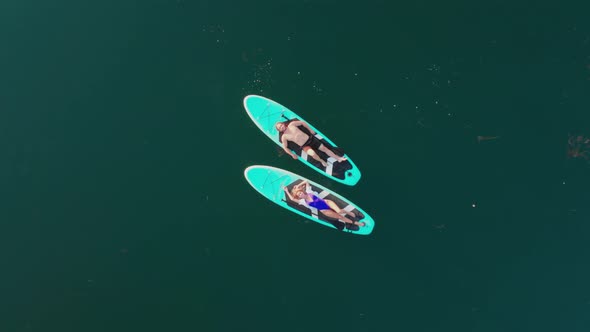 Surfers Couple Lying on Surfing Board Man and Woman Swimmers Relaxing on Blue Surfboards Top View