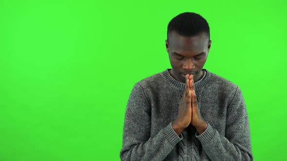 A Young Black Man Prays with Hands Clasped Together - Green Screen Studio