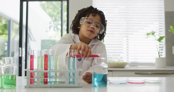 Happy biracial boy making chemistry experiments, holding test tube