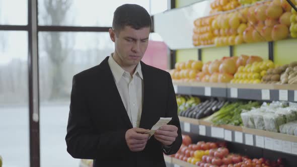 Portrait of Wealthy Caucasian Businessman Examining Price of Food in Bill and Sighing. Young Man in