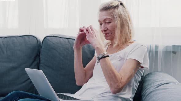 Old Woman Making Heart Shape in Front of the Laptop While Chatting with Her Family