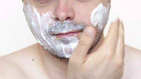 bearded man is applying shaving foam on face. skincare cosmetology concept.morning routine.bottom