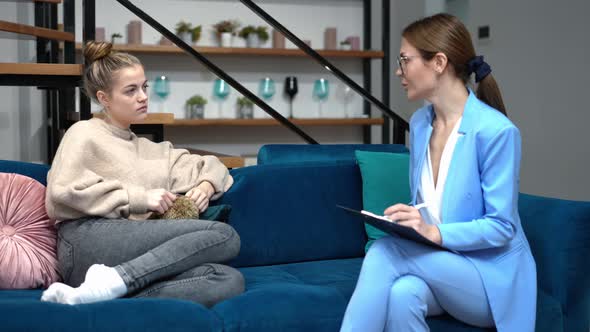 Side View Portrait of Upset Teenage Girl Talking with Professional Psychologist Sitting on Couch