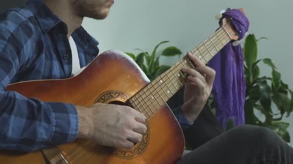 Man playing on acoustic guitar, strumming and picking strings and changing chords. Music concept