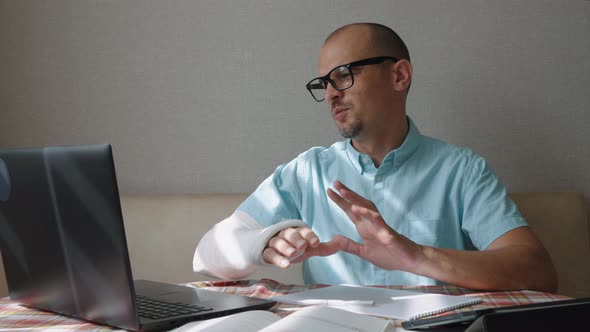 Man with Broken Arm Having Online Meeting