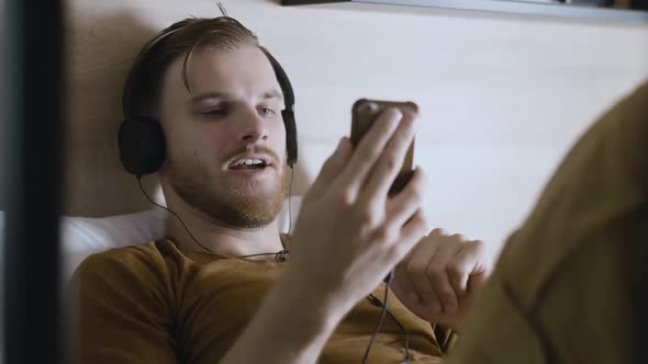 Portrait of Young Positive Man in Headphones Using Video Chat. Cheerful Handsome Caucasian Guy