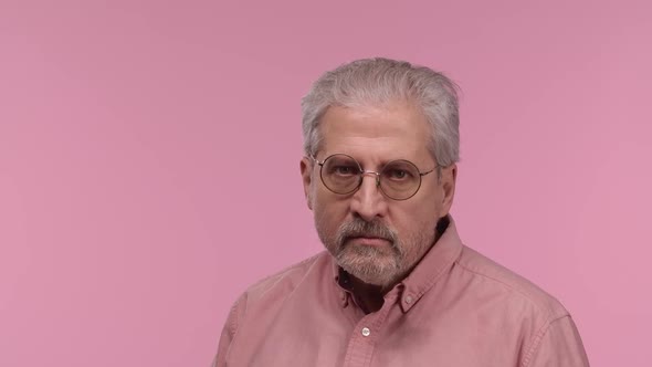 Portrait of an Elderly Man with Glasses Looking at Camera with Anticipation Then Very Upset