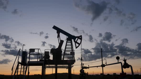 Oil Rig Stands in a Field at Sunset and Extracts Minerals