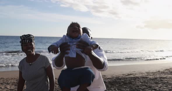 Cheerful african parents enjoy playful moment with little son on the beach outdoor