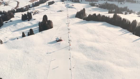 follow drone shot of lone skier on a long ski slope
