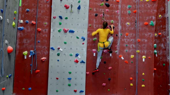 Woman practicing rock climbing in fitness studio 4k