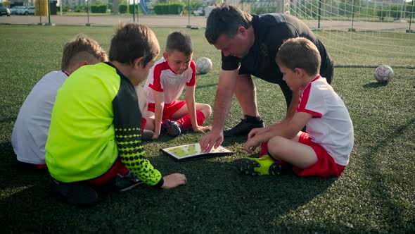 Junior Football Team Coach Shows Children Game Scheme