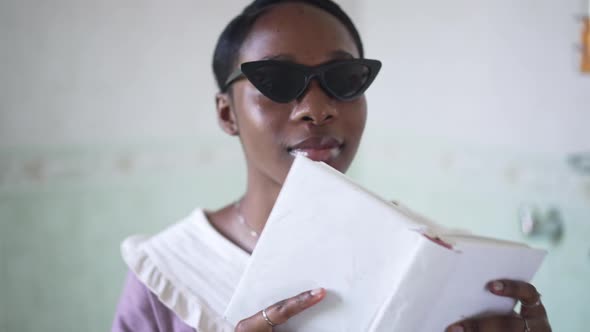 Closeup Book in Female African American Hands Putting Down and Young Happy Woman in Sunglasses