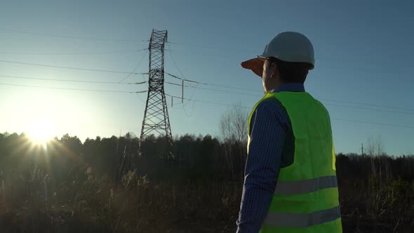 An Energy Engineer in Special Clothing Checks the Power Line