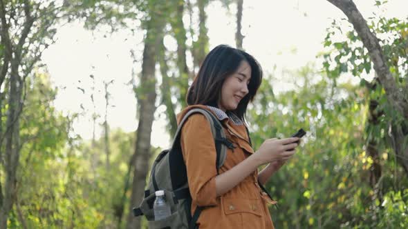 Smiling young Asian woman tourists using smartphones in the forest.