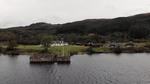 Horses graze near Scotland flag waving from pier on Loch Ness, aerial