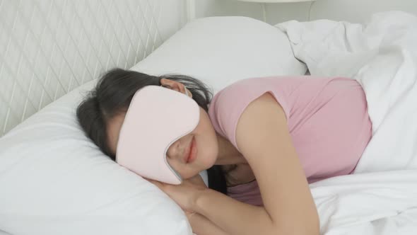 Beautiful young asian woman wearing cover eye and sleeping on bed with head on pillow comfort.