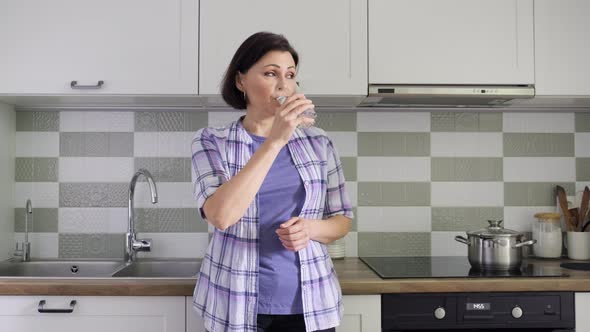 Mature Woman with a Glass of Water in the Kitchen