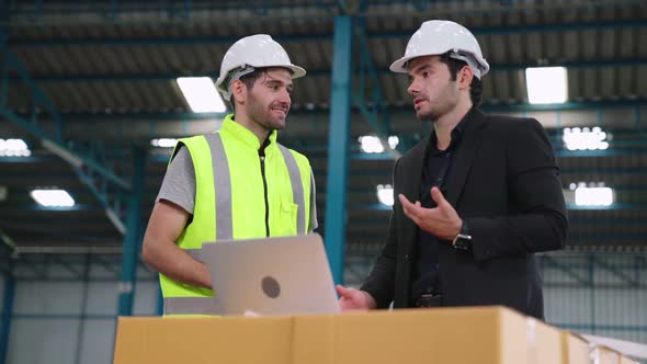 Two Factory Workers Working and Discussing Manufacturing Plan in the Factory