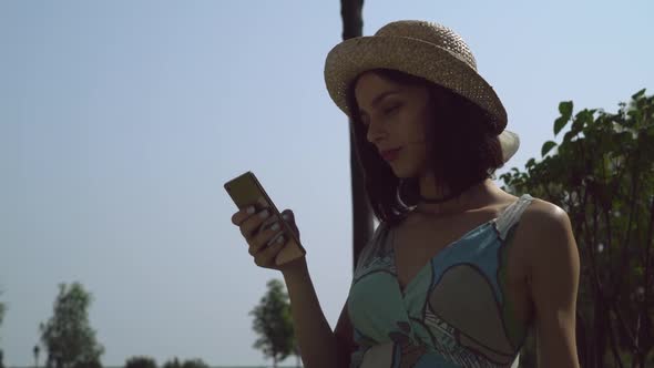 A Young Girl in a Hat Gaining a Message on the Phone.