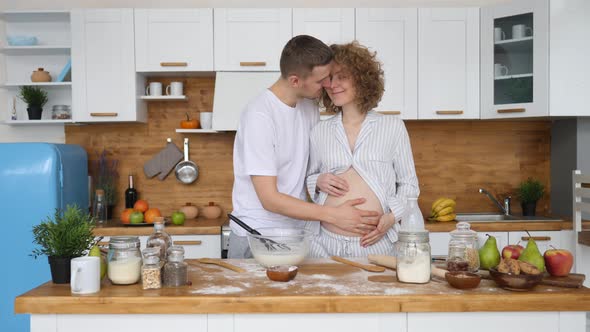 Pregnant Woman And Her Husband Preparing Meal On Kitchen