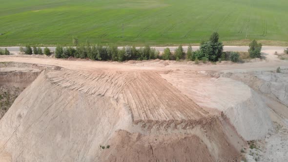 Flight over sand quarry mining and green field.