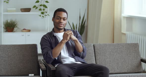 Afro American Guy Sits at Home in Living Room on Couch Watching Tv Sports Match Online Through