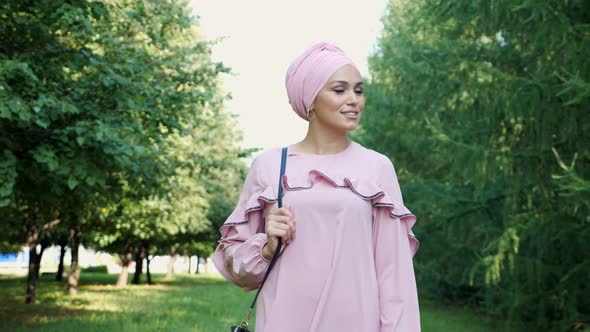 Girl in Long Purple Dress and Hijab Wanders Along Park