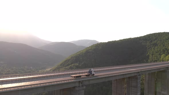 Aerial View of Truck with Flatbed Trailer Driving on Highway Viaduct in the Mountains