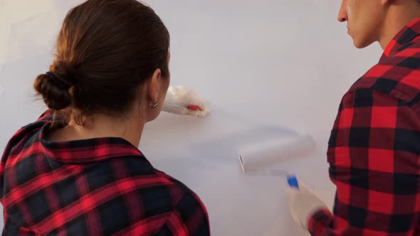 Young Family of Woman and Man Paints Wall in Light Grey