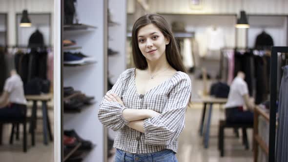 A Front View Close Up Shot of a Young Beautiful Woman Standing in a Clothing Boutique Lookin