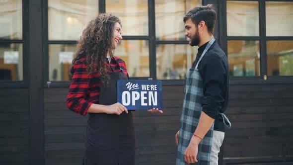 Slow Motion Portrait of Two Happy Entrepreneurs Cafe Owners Posing with Open Sign in Front of New