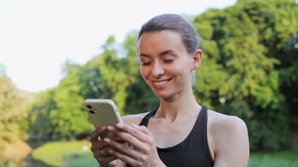 Happy Beautiful Woman Standing in the Park Using Mobile Phone App at Sunset