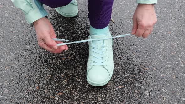 Senior Old Caucasian Woman Laces Her Shoes Before Running in The Snowy Winter Park