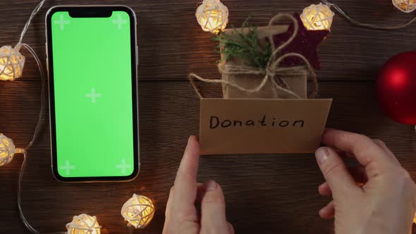 Christmas Donation Concept Hand Writing Gift Card and Green Screen Smartphone