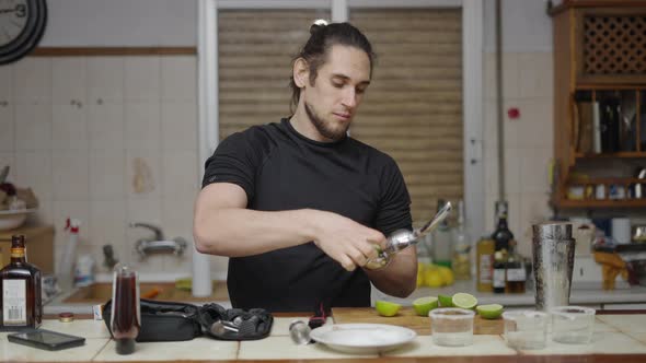 Young Attractive Barman Using Lemon Squeezer to Obtain Juice for Cocktail