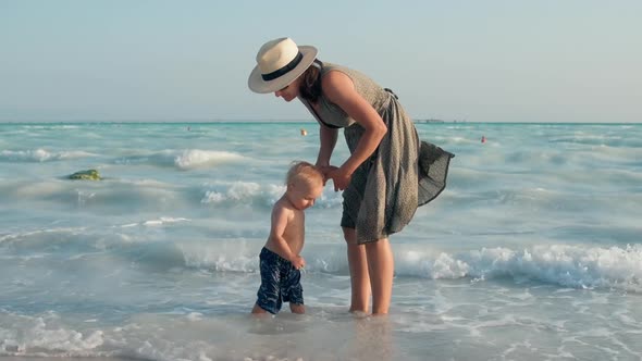 Happy Mother and Child Going From Water at Seashore