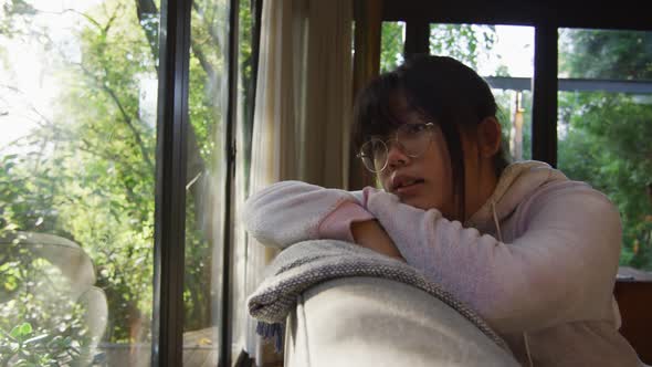 Asian girl looking through window and lying on couch