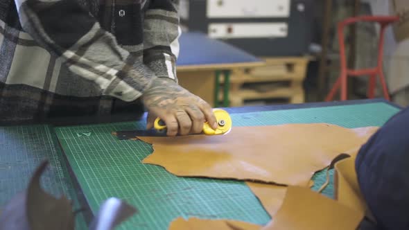 Hands of Shoemaker Cutting Artificial Brown Leather in Studio